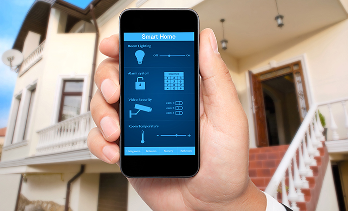 male hand hold a phone with system smart house on a screen on the background of the house